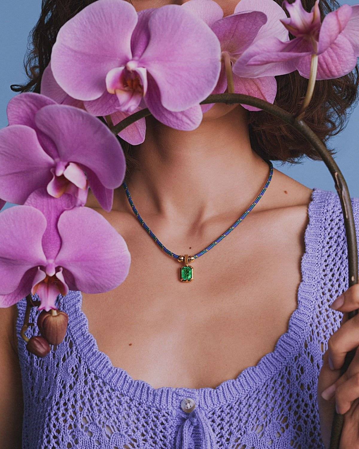 Model holding pink orchids, wearing the Kathryn Emerald Pendant