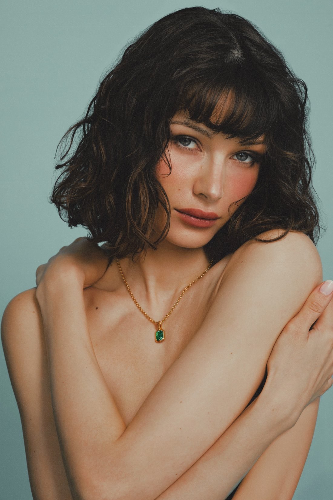 Model with a curly bob, arms crossed, wearing the Kathryn Emerald Pendant